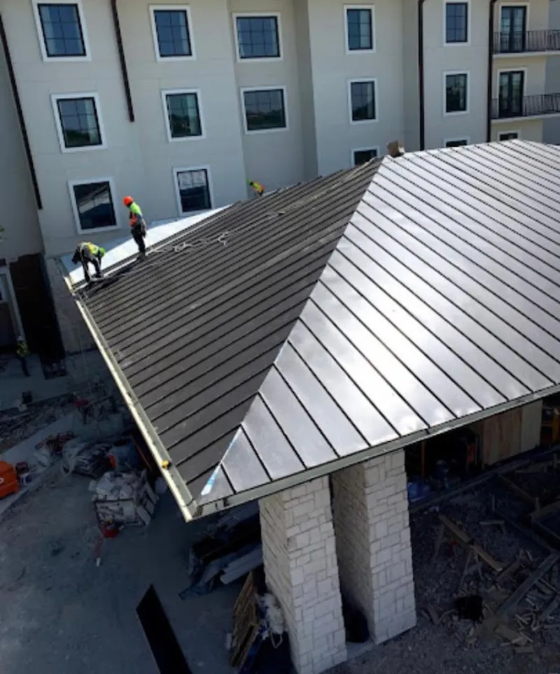 Crew installing standing seam metal roof panels on a commercial project in Monona